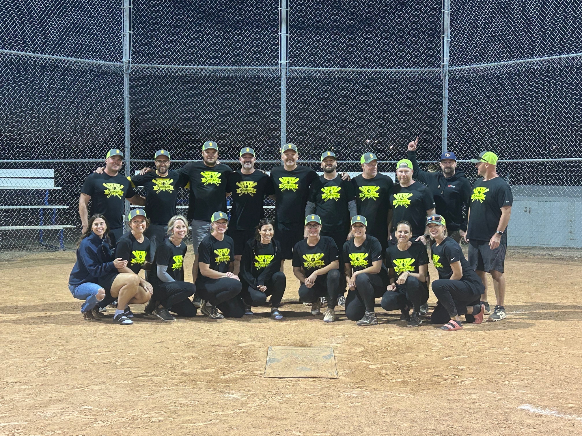 The winning slo-pitch players wearing black shirts with the yellow team logo, The Swingers.