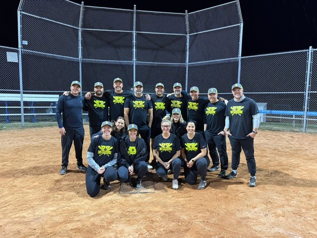 The winning slo-pitch players wearing black shirts with the yellow team logo, The Swingers.